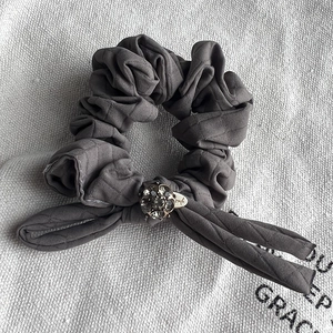Detail of grey quilted fabric hair scrunchie with sparkling rhinestone sphere ornament