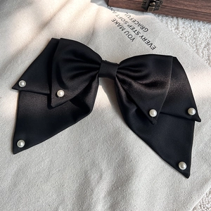 Detail einer eleganten schwarzen Satin-Schleifen-Haarspange mit Perlen auf Canvas-Hintergrund