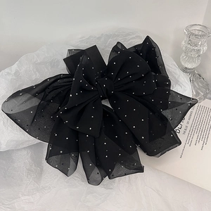 Detail of elegant black mesh bow hair clip with sparkling silver rhinestones on white background