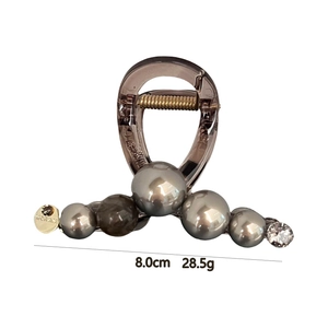 Detail view of smoky grey resin hair claw clip with faux pearls and gold pendant charms