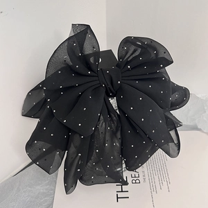 Macro shot of large black chiffon hair bow with tiny shimmering rhinestones and layered fabric