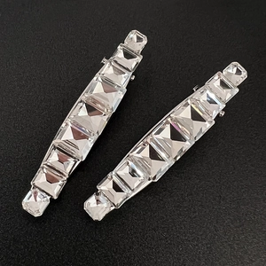 Macro de deux pinces à cheveux argentées avec strass en cristal sur fond noir texturé