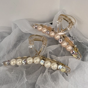 Grandes pinces à cheveux en résine avec perles et strass sur fond blanc texturé élégant