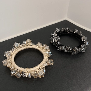 Detailed view of handmade crystal elastic hair ties in beige and black colors