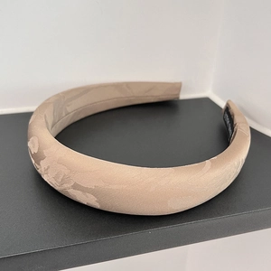 Detailed view of champagne jacquard padded headband with floral pattern and handmade label