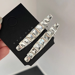 Gros plan de deux barrettes à cheveux en cristal avec strass carrés sur carte noire