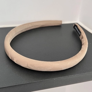 Detailed shot of beige foam headband showing refined texture and handmade inner label