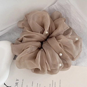 Detail of mocha brown pleated organza scrunchie with elegant pearl beads on white background