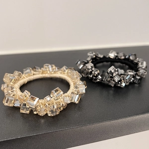 Close-up of premium crystal ponytail holders in champagne gold and black hand-woven styles