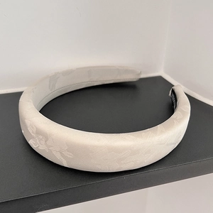 Detail showing jacquard floral texture and handmade label on the cream hairband