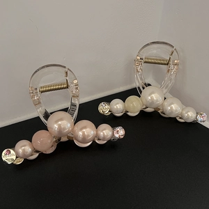 Detail of elegant faux pearl hair claws in champagne and white with rhinestone accents