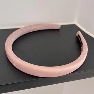 Detailed close-up of a lotus pink padded headband with handmade label and satin fabric