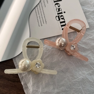 Detalle de pinzas de acetato para el cabello en crema y rosa con perlas y flores de strass