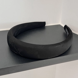 Detail of a handmade black wide-brimmed fabric headband showing the Hand Made inner label