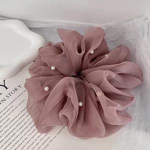 Detailed view of dusty rose organza hair scrunchie with embedded elegant white pearls