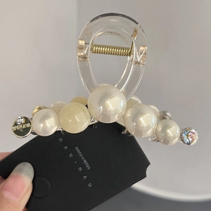 Detailed close-up of premium faux pearl and zircon hair claw clip with gold branding