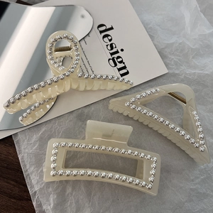 Detail of three pearl and rhinestone hair claws with ivory resin and French elegant finish