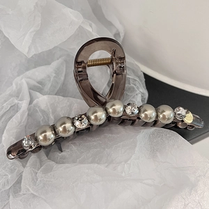 Vue macro de la pince à cheveux en acrylique gris fumé avec perles et strass brillants