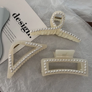 Detailed macro view of cream resin hair claws with faux pearls and sparkling rhinestones