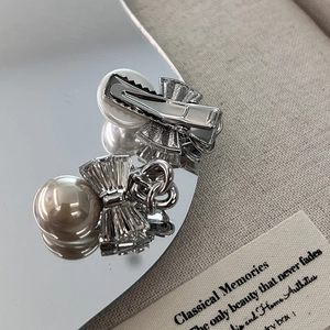 Bow hair clip with imitation pearls and glass diamonds on a reflective mirror surface