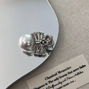 Elegant silver hair clip with faux pearl and rhinestone bow on reflective mirror base