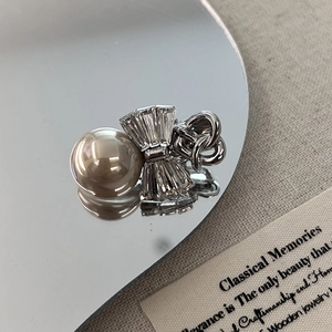 Detail of elegant bow hair clip with large cream pearl and crystals on a mirror