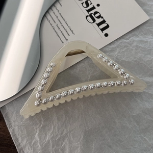 Macro shot of triangle hair claw clip with pearls and rhinestones on aesthetic background