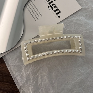 Close-up of elegant cream resin hair claw clip with pearls and sparkling rhinestones