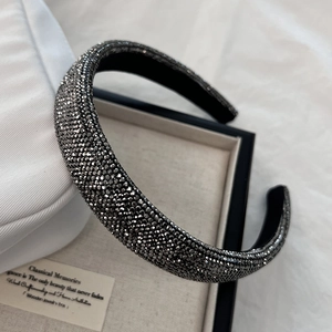 Gros plan d'un serre-tête rembourré de luxe avec strass foncés et doublure noire