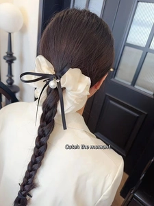 Elastico per capelli in seta bianca con fiocco nero e perla su capelli intrecciati