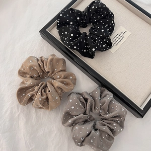 Detailed view of luxury black, khaki, and grey satin scrunchies with sparkling rhinestones