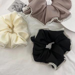 Three elegant satin hair scrunchies in cream, brown, and black with delicate pearl edges