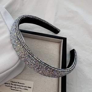 Détail d'un serre-tête large de luxe avec des strass AB scintillants sur un plateau décoratif