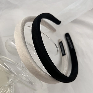 Detailed view of handmade fabric headbands in black and cream on a glass base