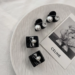 Détail de quatre pinces à cheveux noires avec perles et nœuds dans un plateau