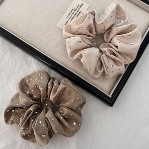 Close-up of luxury velvet hair scrunchies in champagne and brown with sparkling rhinestones