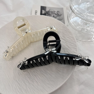Close-up of black and cream bow hair claws on a marble plate with elegant aesthetic