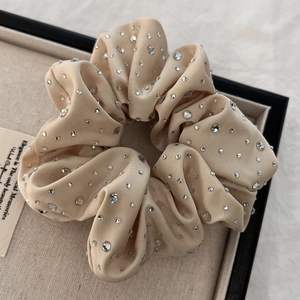 Close-up of champagne satin scrunchie with sparkling rhinestones on a display tray