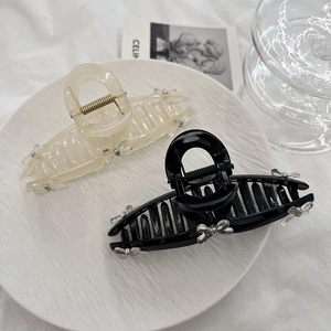 Elegant large hair claw clips in black and beige with delicate bow details