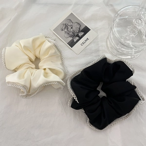 Detail of cream and black satin hair scrunchies with delicate pearl trim embellishments