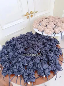 Dettaglio di scrunchies in raso con eleganti perle e nastri in blu navy e rosa champagne