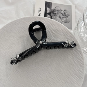 Macro shot of large black hair claw clip with transparent bows and silver bead details