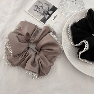 Detailed close-up of satin and lace hair scrunchies with elegant pearl embellishments