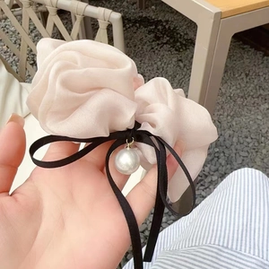 Dettaglio dell'elastico in chiffon rosa con fiocco nero e ciondolo di perla