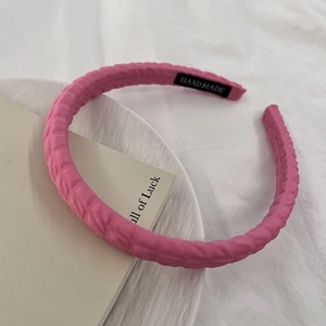 Detail eines rosa gesteppten Haarreifs mit handgefertigtem Etikett und weicher Textur