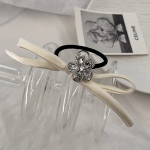 Close-up of elegant cream satin bow hair tie with crystal flower detail and black elastic