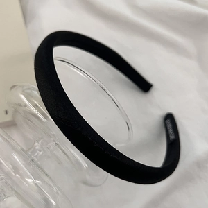 Detail of handmade black fabric headband with satin texture on elegant glass base