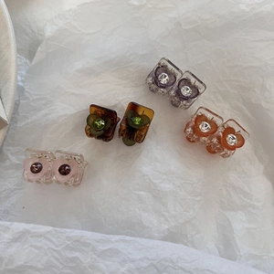 Mini pinces à cheveux fleurs avec strass en plusieurs couleurs sur fond blanc texturé