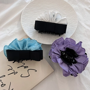 Detailed view of elegant large bow hair claws in cream, light blue, and lilac fabric