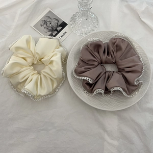 Close-up of elegant satin scrunchies with white pearl edges in cream and taupe